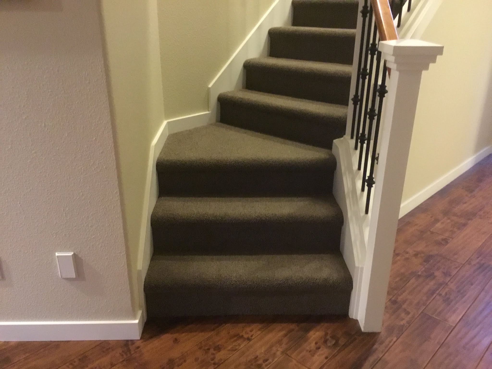 A finished upstairs hallway landing with dark carpet and iron railing