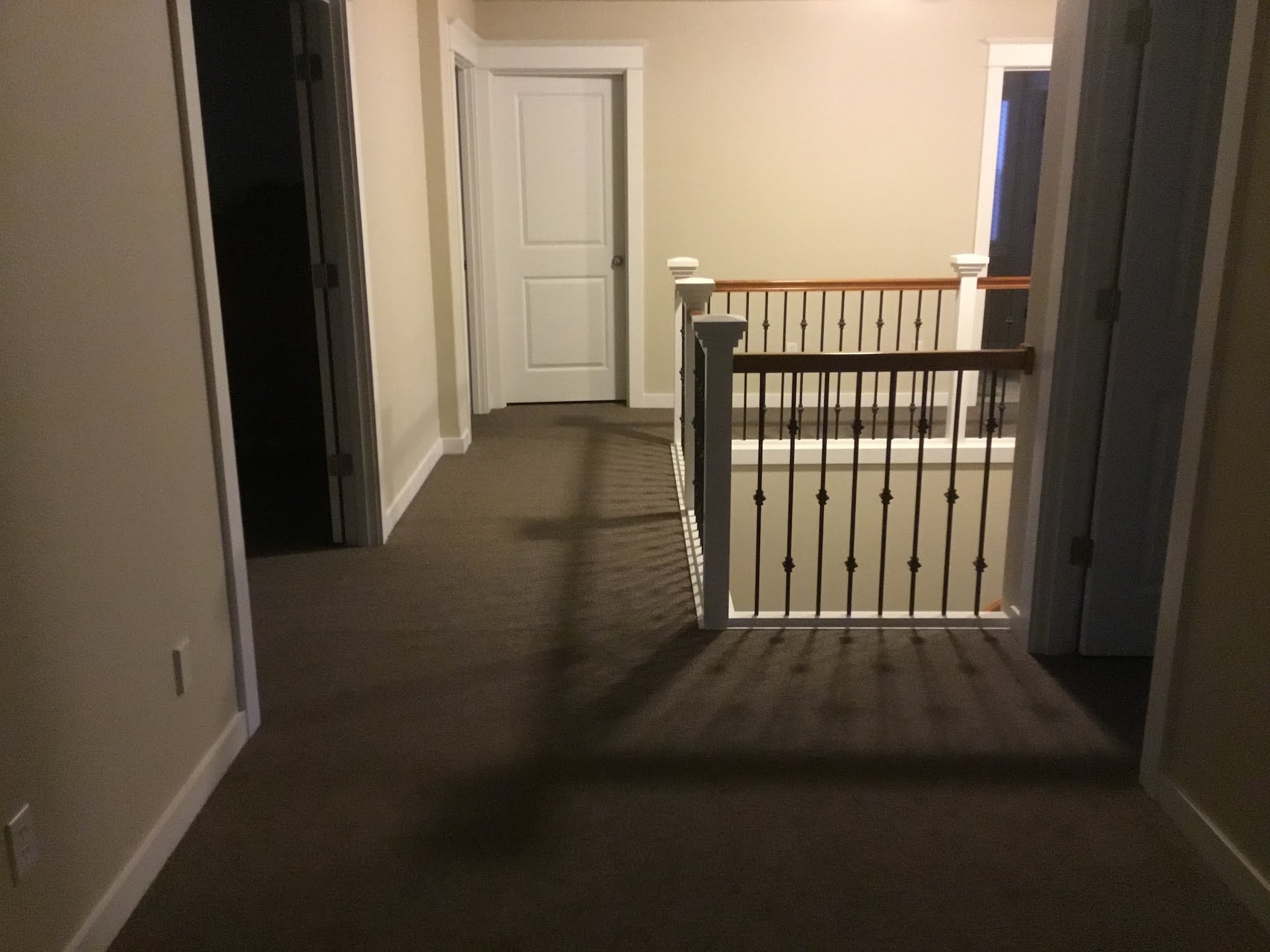 A finished staircase with carpet treads and a wood handrail against white walls